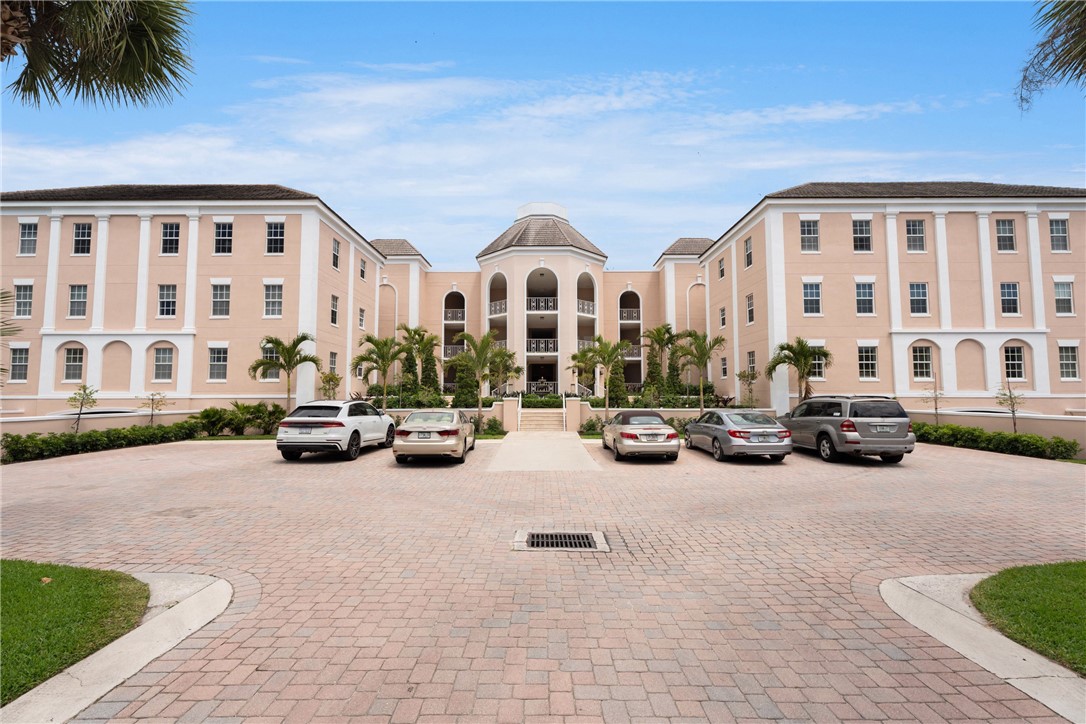 Grand classical-style building featuring symmetrical wings, a central domed rotunda, multiple balconies, and a paved brick entrance