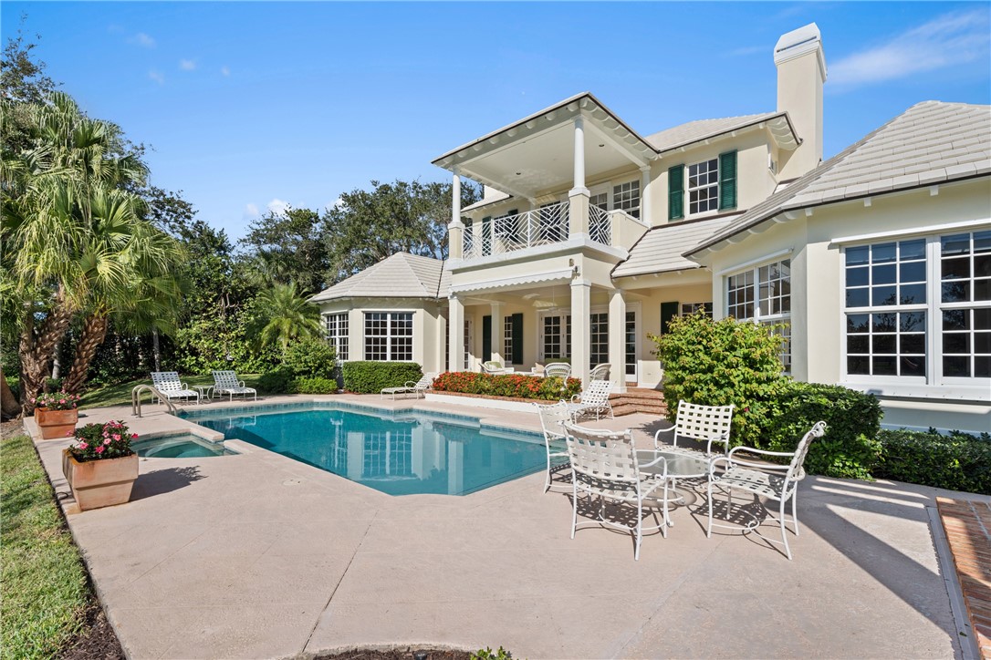 Expansive outdoor living area featuring a rectangular pool and spa, surrounded by a concrete deck
