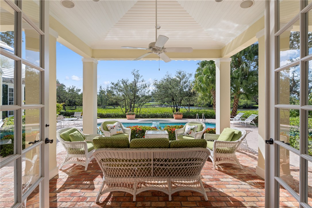 Covered outdoor patio featuring a brick paver floor, vaulted beadboard ceiling, and a ceiling fan