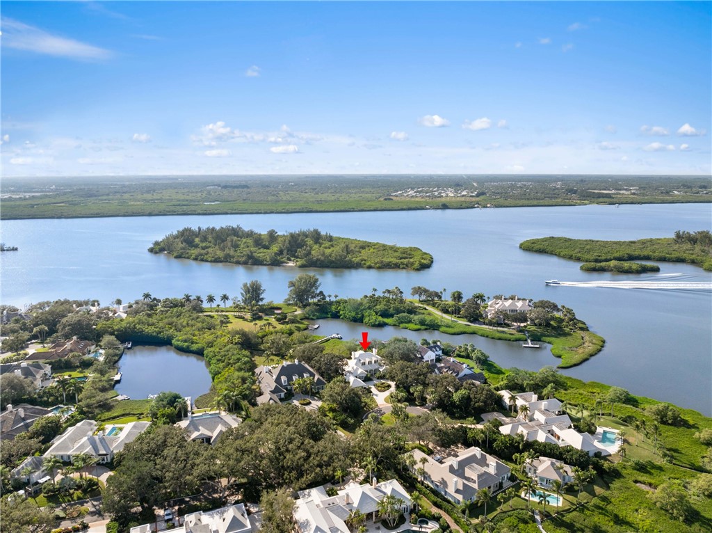 Waterfront property featuring a private boat dock, mature landscaping, and an expansive natural water setting
