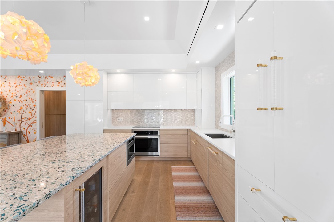 Modern kitchen featuring a spacious island with a light-toned countertop, a built-in beverage cooler, and light wood-finish cabinetry