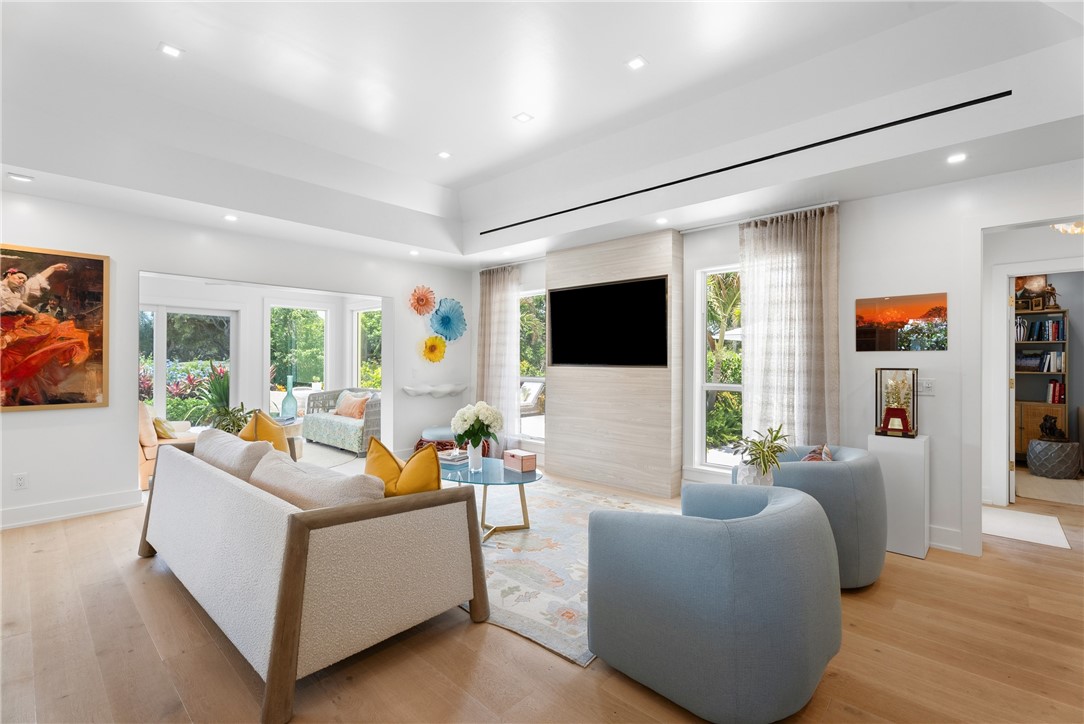 Spacious living area featuring light wood-finish flooring, recessed lighting, and large windows with outdoor landscaping