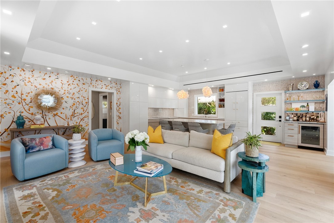 Spacious open-concept living area featuring light wood-finish flooring, recessed lighting, and a decorative accent wall
