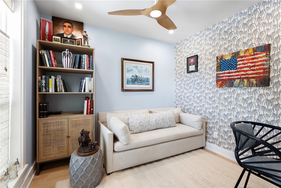Versatile room featuring a light wood-finish ceiling fan with integrated lighting, a built-in shelving unit with lower cabinet storage, and a striking patterned accent wall