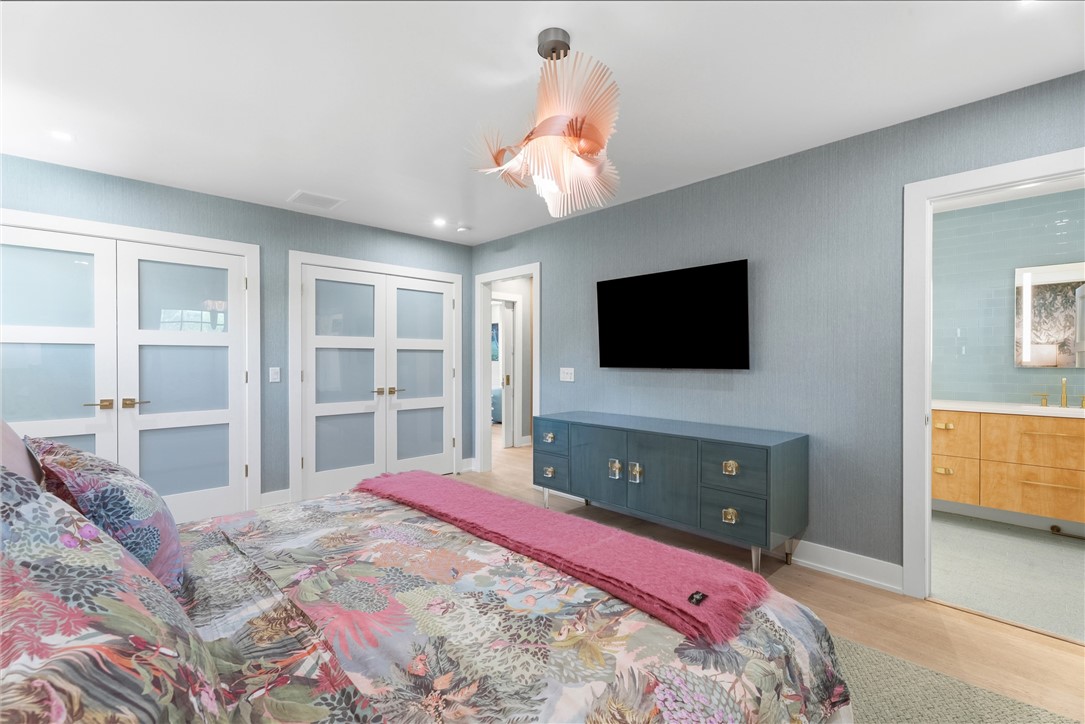 Bedroom with light blue textured wall covering and wood-finish flooring