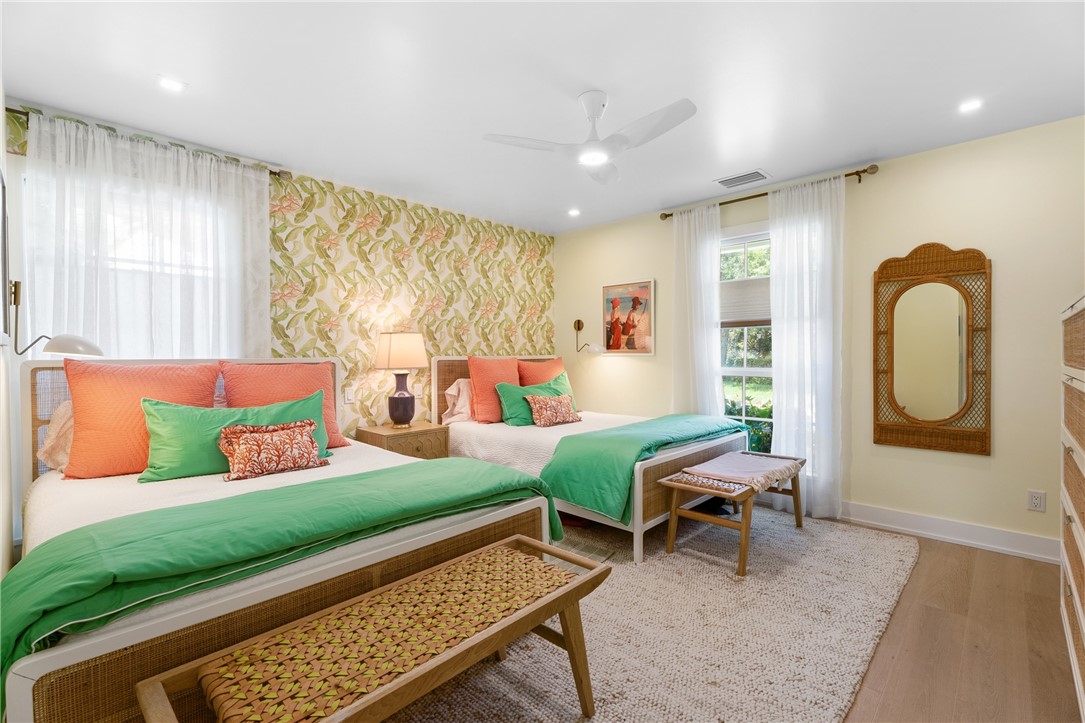 Bedroom featuring a tropical-patterned accent wall and light yellow painted walls