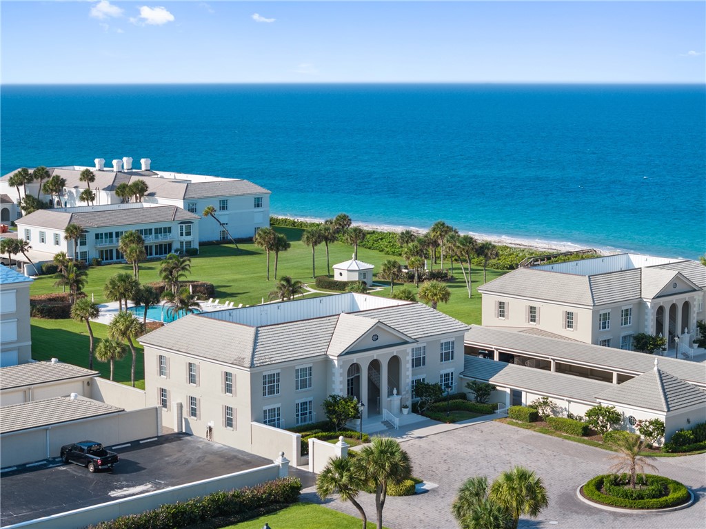 Expansive oceanfront property featuring a private beach, multiple residential structures, a resort-style swimming pool, and extensive palm-lined grounds