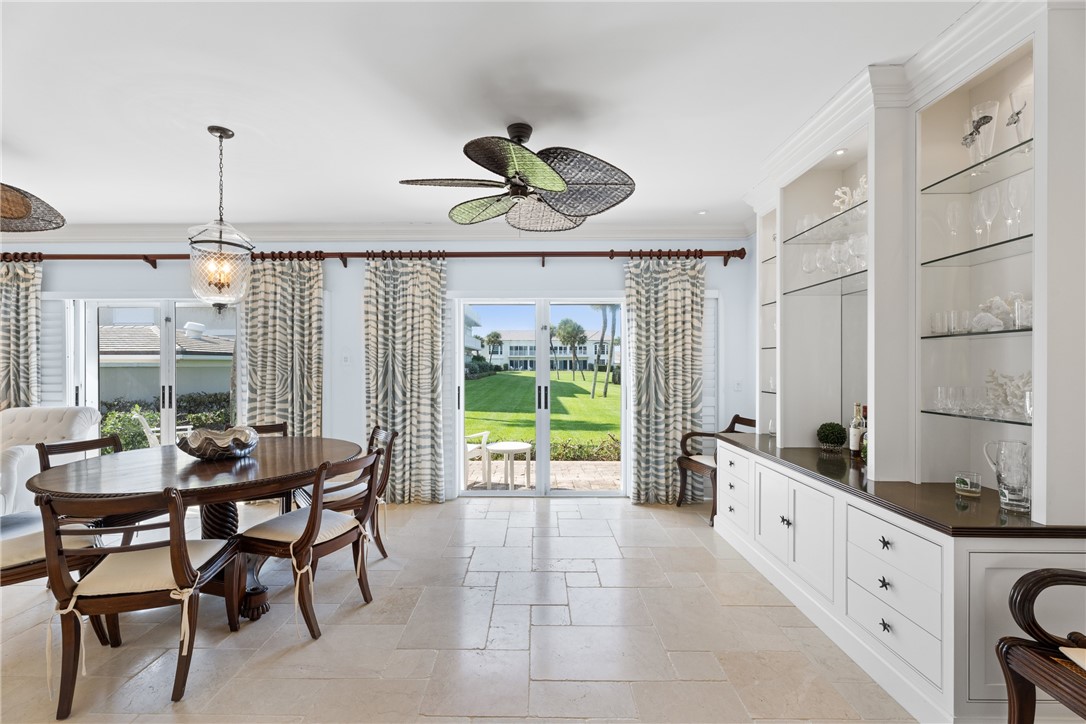 Spacious interior featuring light-colored tile flooring, full-height built-in cabinetry with glass shelving, and sliding glass doors opening to a manicured lawn