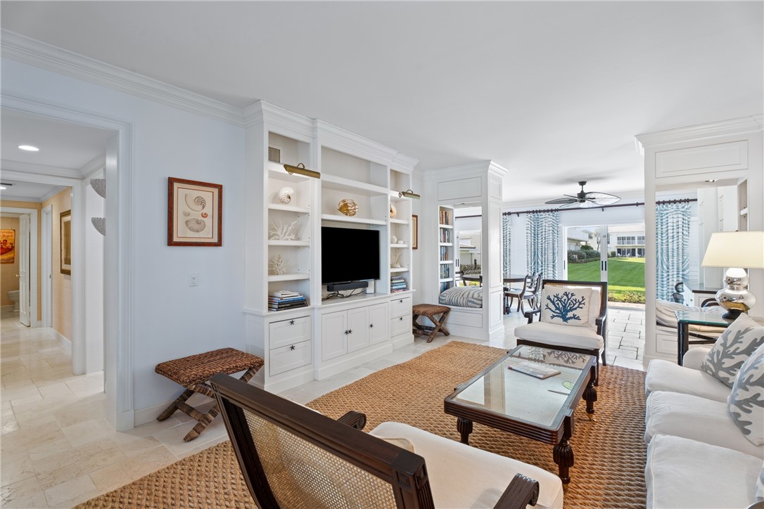 Living area featuring a custom built-in entertainment center with integrated lighting, crown molding, and light-toned flooring