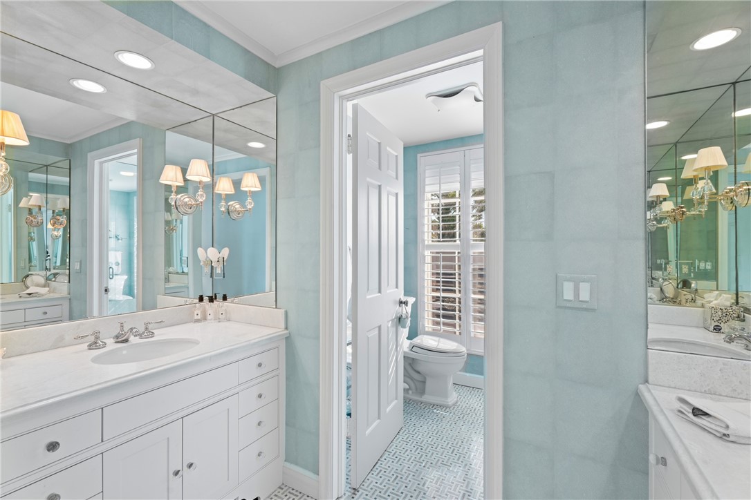 Bathroom vanity featuring white cabinetry with brushed chrome hardware, a white countertop, and an undermount sink with a chrome faucet