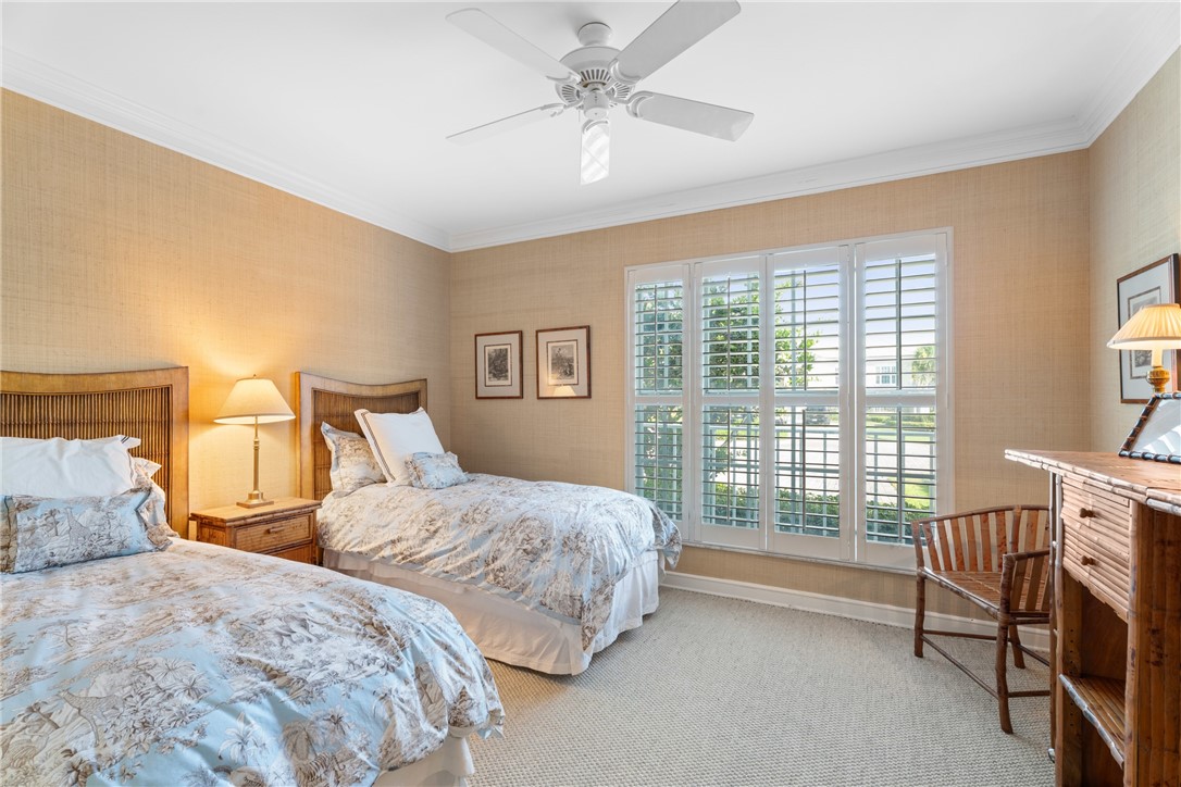 Bright room featuring a large window with white plantation shutters, crown molding, and textured wall coverings