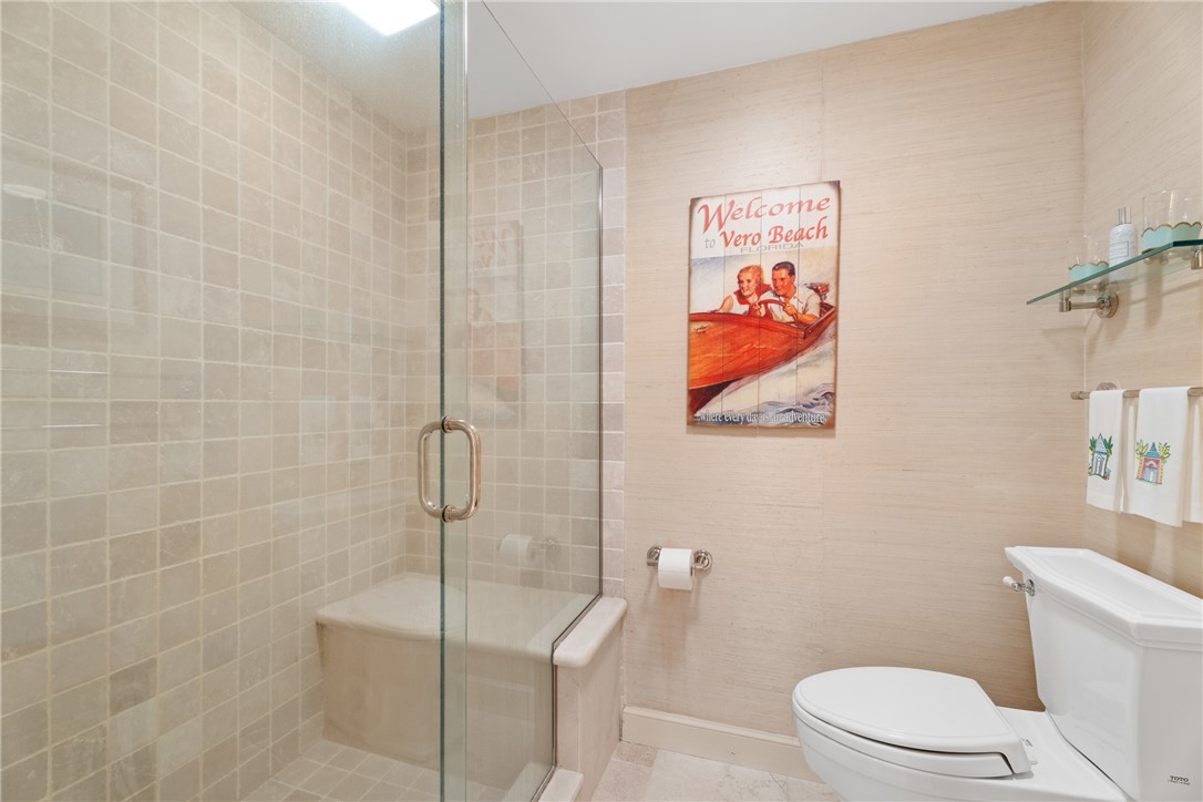 Glass-enclosed shower featuring full-height square tile surround and a built-in bench