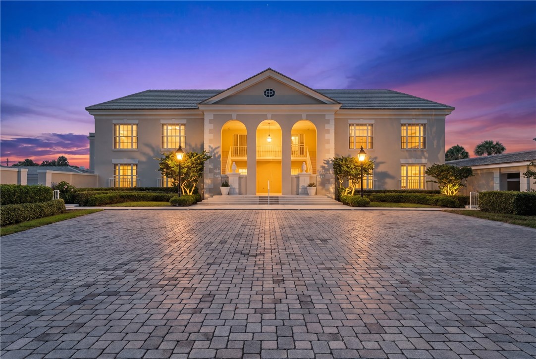 Stately two-story residence with a grand portico featuring three arches, a central balcony, and column accents