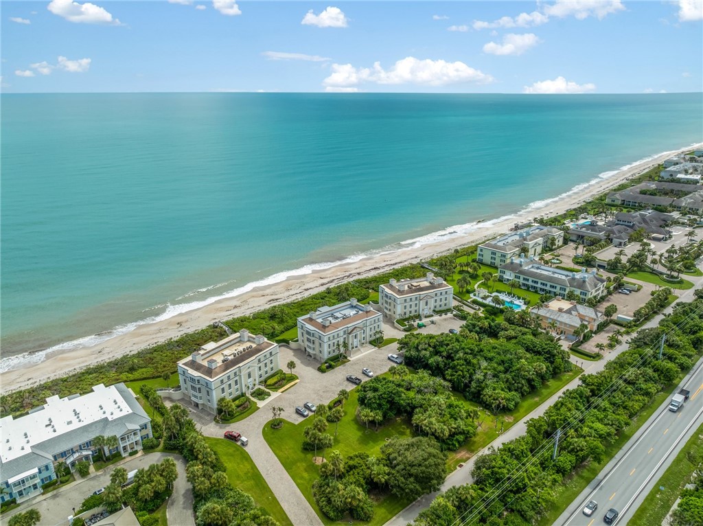 Oceanfront property with direct beach access, resort-style swimming pool, lush landscaping, and private parking
