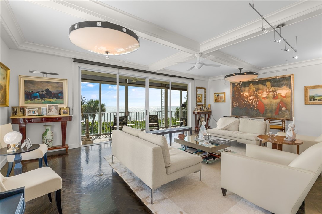 Hardwood-finish flooring, recessed ceiling with decorative beams, sliding glass doors, built-in ceiling lighting, and a ceiling fan