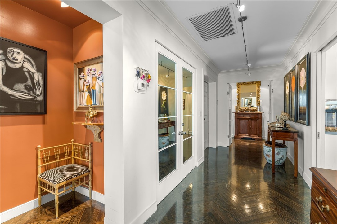 Herringbone wood-finish flooring, crisp white walls, track lighting, and French doors