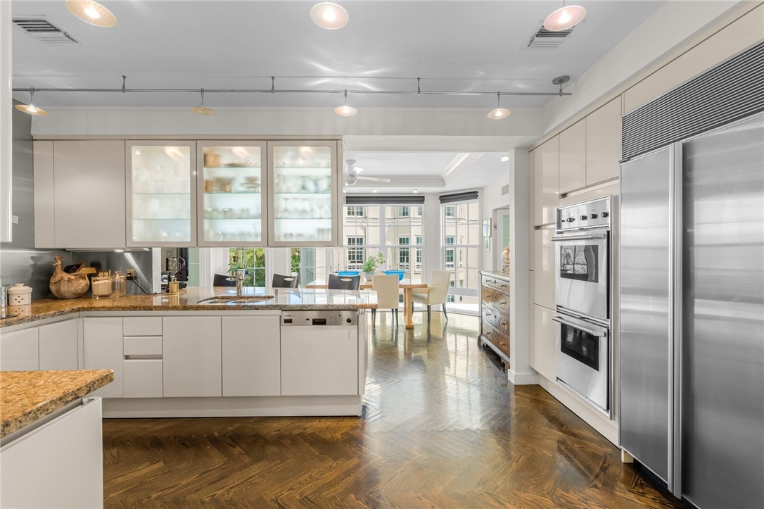 Gourmet kitchen featuring stainless steel appliances, double ovens, built-in refrigerator, and wood-finish herringbone flooring