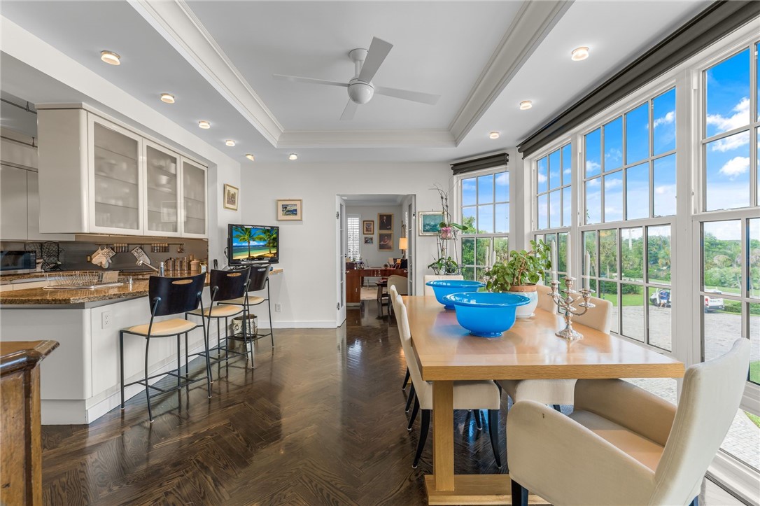 Open-concept living space featuring expansive windows with natural light, dark wood-finish flooring throughout, and a generous dining area