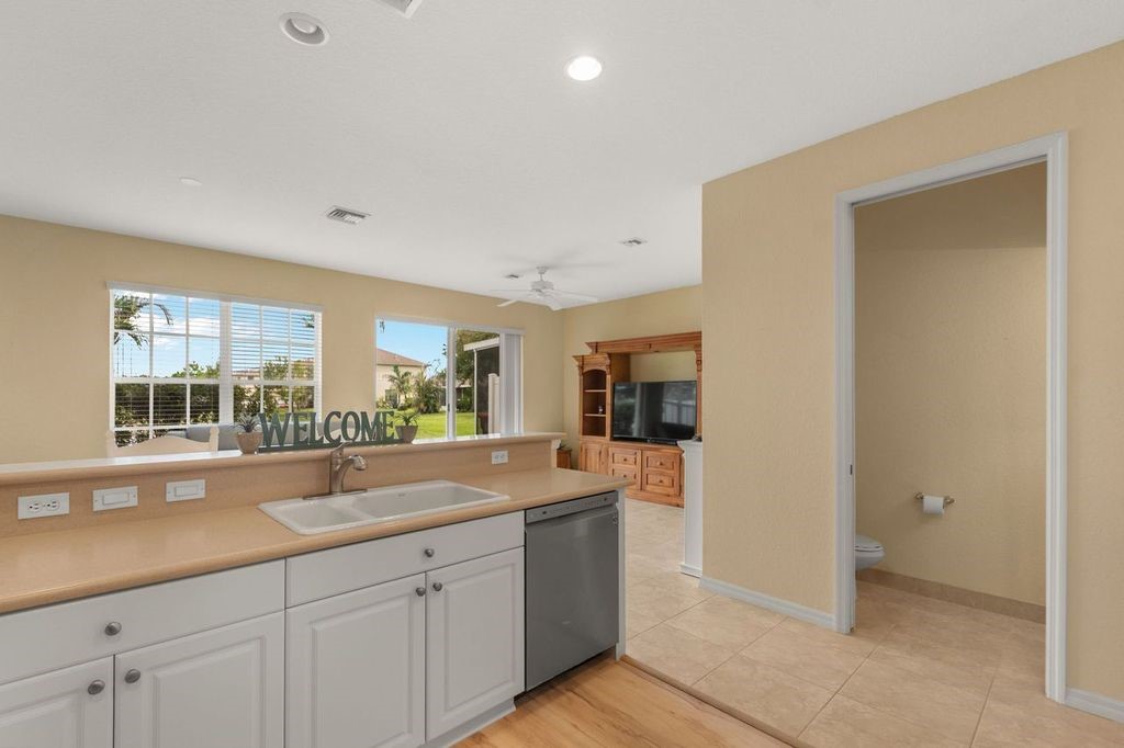 Kitchen featuring a double basin sink, white cabinetry, integrated dishwasher, and countertop space
