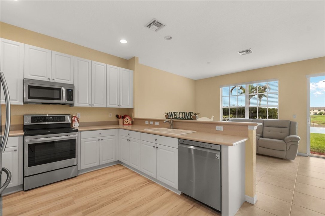 Kitchen featuring white cabinetry, stainless steel appliances, wood-finish flooring, and a breakfast bar