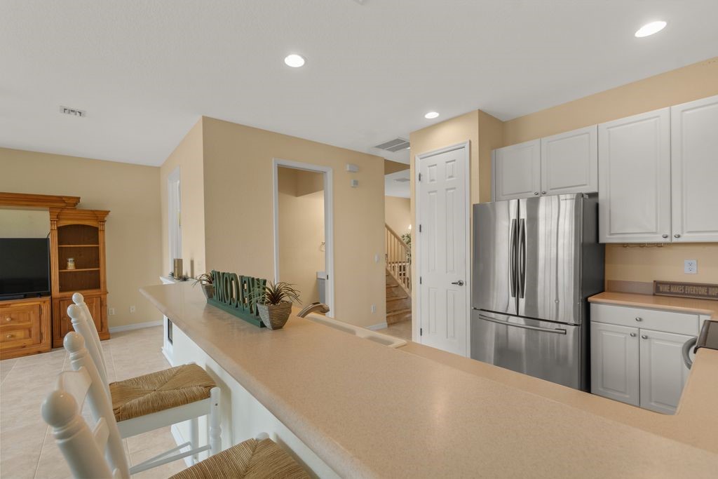 Kitchen featuring white cabinetry, light-toned countertops, and a stainless steel refrigerator