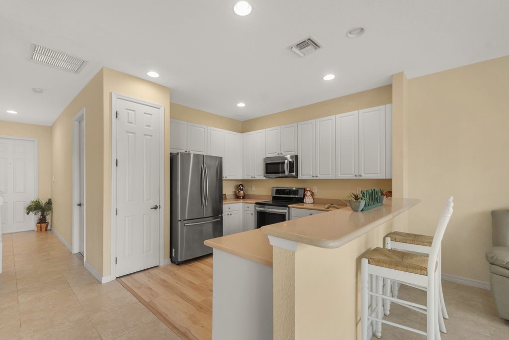 Kitchen featuring white cabinetry, stainless steel appliances, recessed lighting, a breakfast bar, and wood-finish flooring