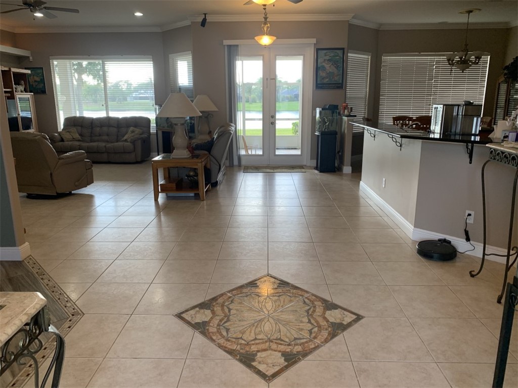 Neutral tone tile flooring with decorative inlay, French doors, recessed lighting, and built-in breakfast bar