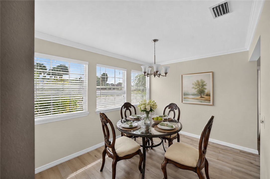 Multiple windows with blinds, crown molding, wood-finish flooring, and a chandelier