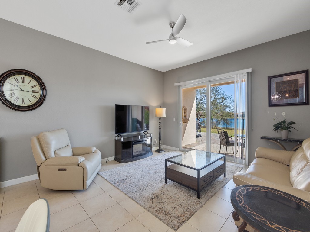 Sliding glass doors opening to a patio, a modern ceiling fan, and tile flooring