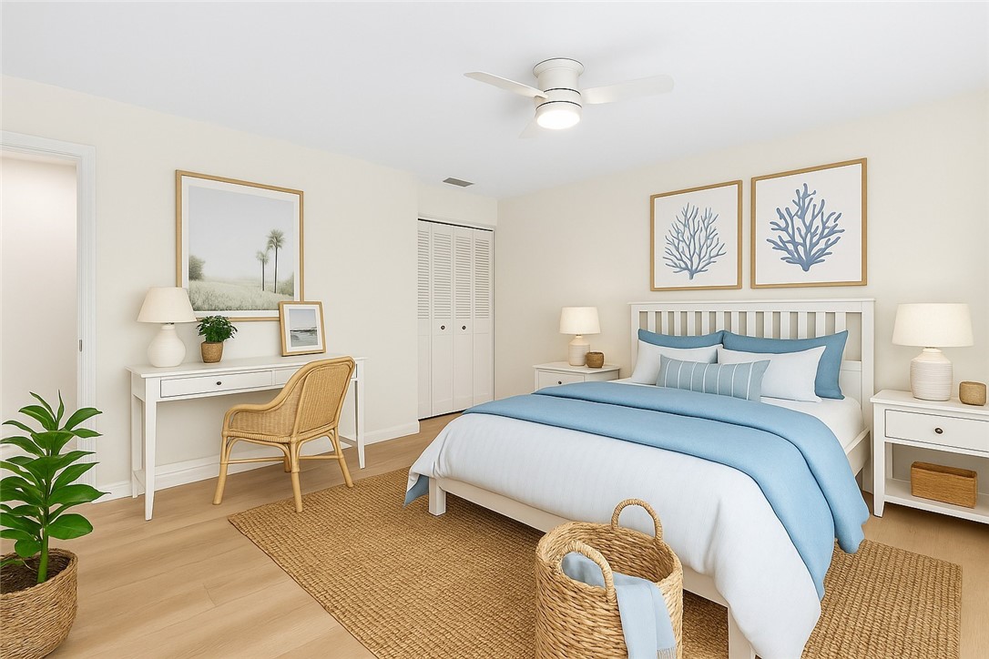 Light-toned wood-finish flooring, white ceiling fan with integrated lighting, louvered bi-fold closet doors, white paneled headboard, and built-in white nightstands