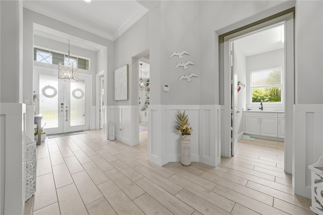 Recessed entryway with double glass-paneled doors, transom window, and overhead chandelier