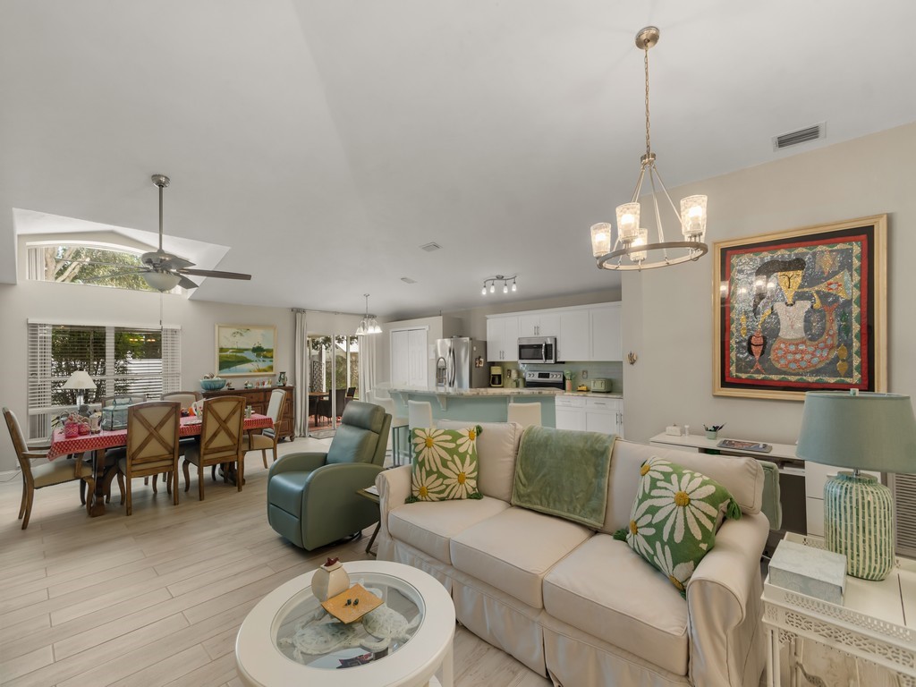 Open-concept living space featuring wood-finish flooring, a contemporary chandelier, and a ceiling fan