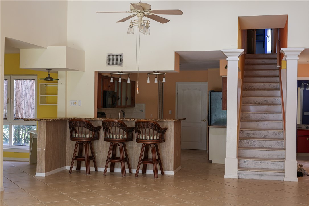 Tiled flooring throughout, kitchen pass-through with granite-look counter, overhead lighting, and built-in cabinetry