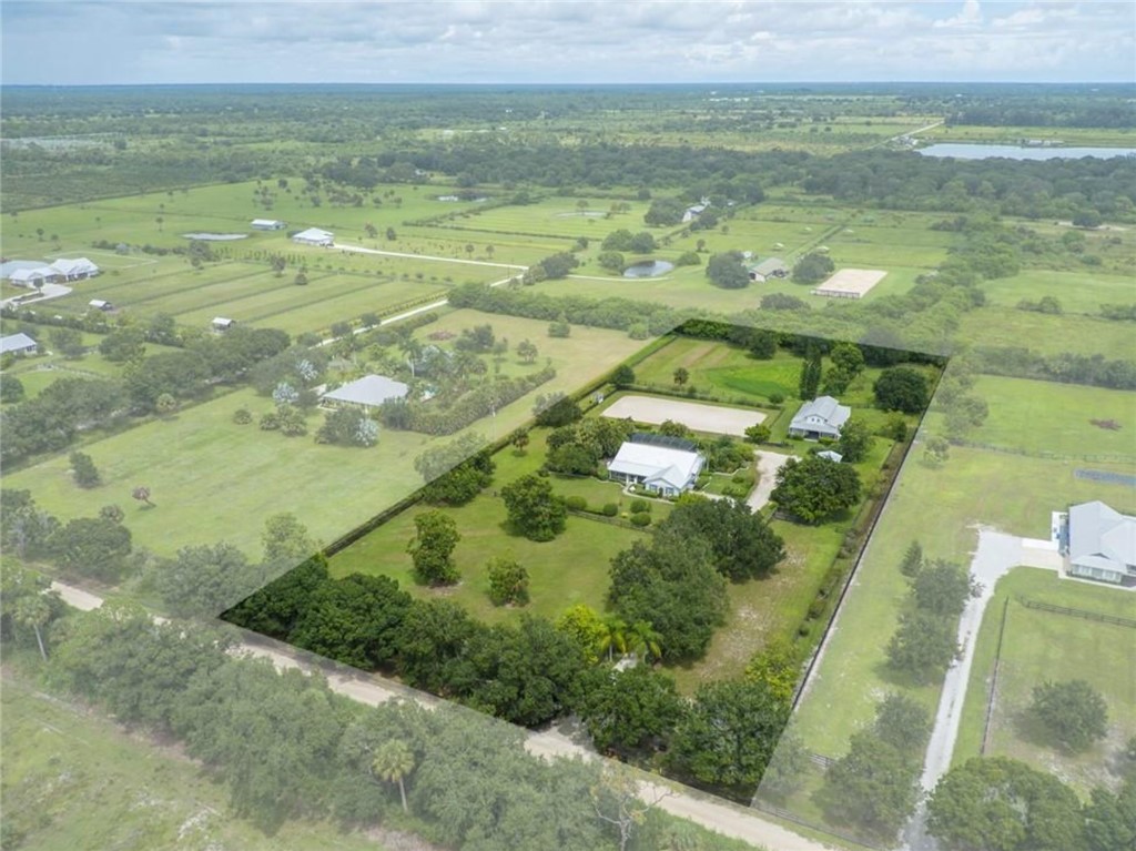 Expansive property featuring two residences, significant green space, mature trees, and a defined perimeter