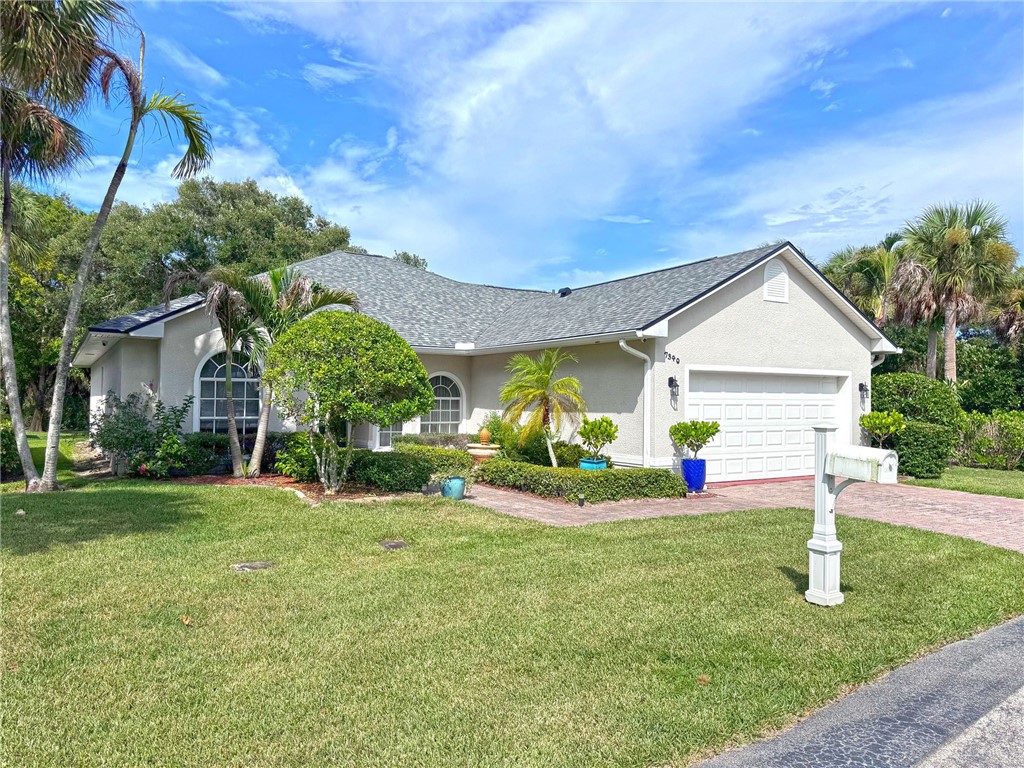 Stucco exterior with a shingle roof, arched windows, an attached two-car garage, and a brick paver driveway