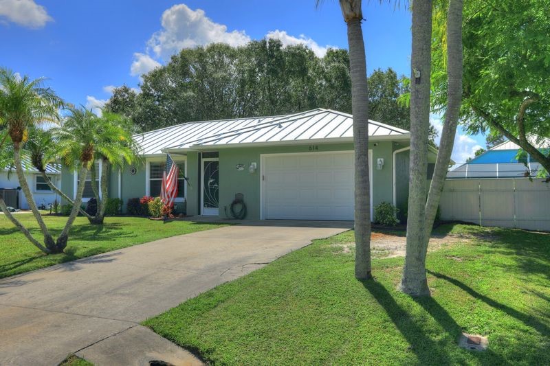 Single-story residence featuring a white metal roof, attached garage, and a concrete driveway
