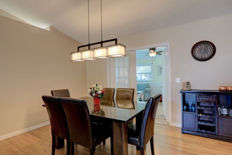 Vaulted ceiling with accent lighting, wood-finish flooring, and a modern rectangular chandelier
