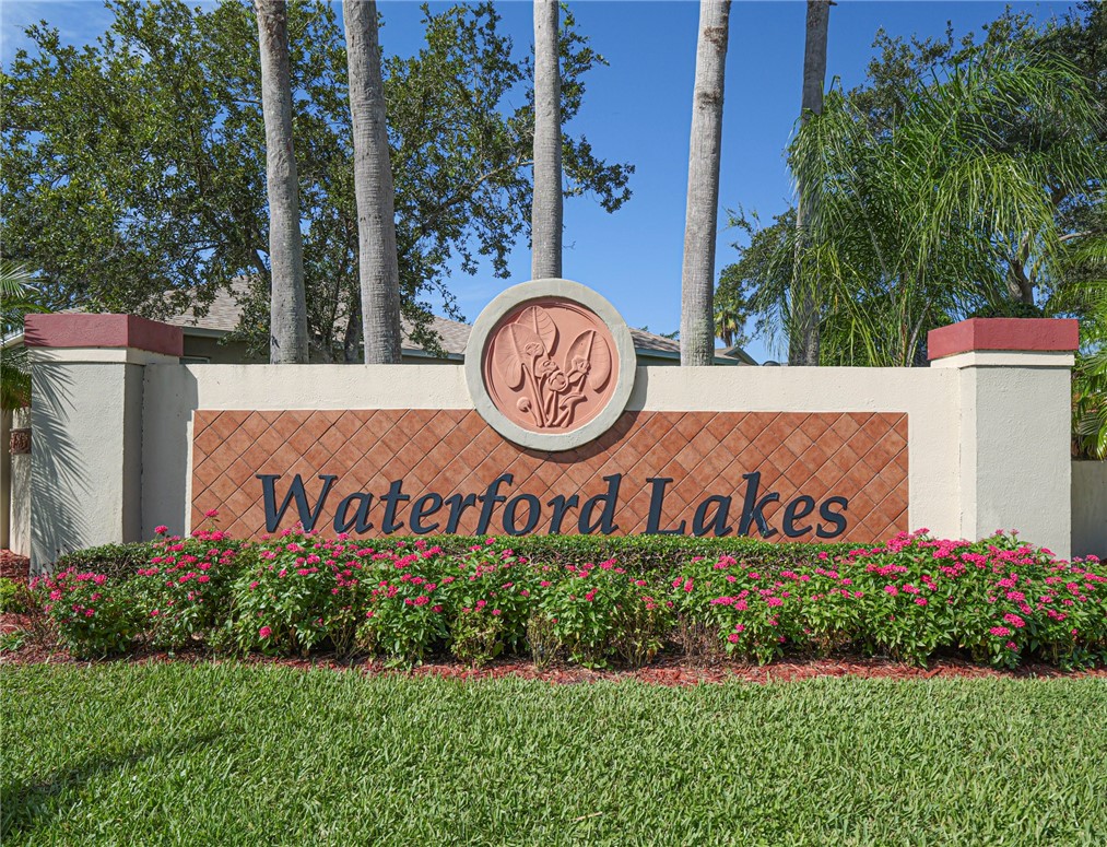 Community entrance sign featuring decorative tile and mature landscaping