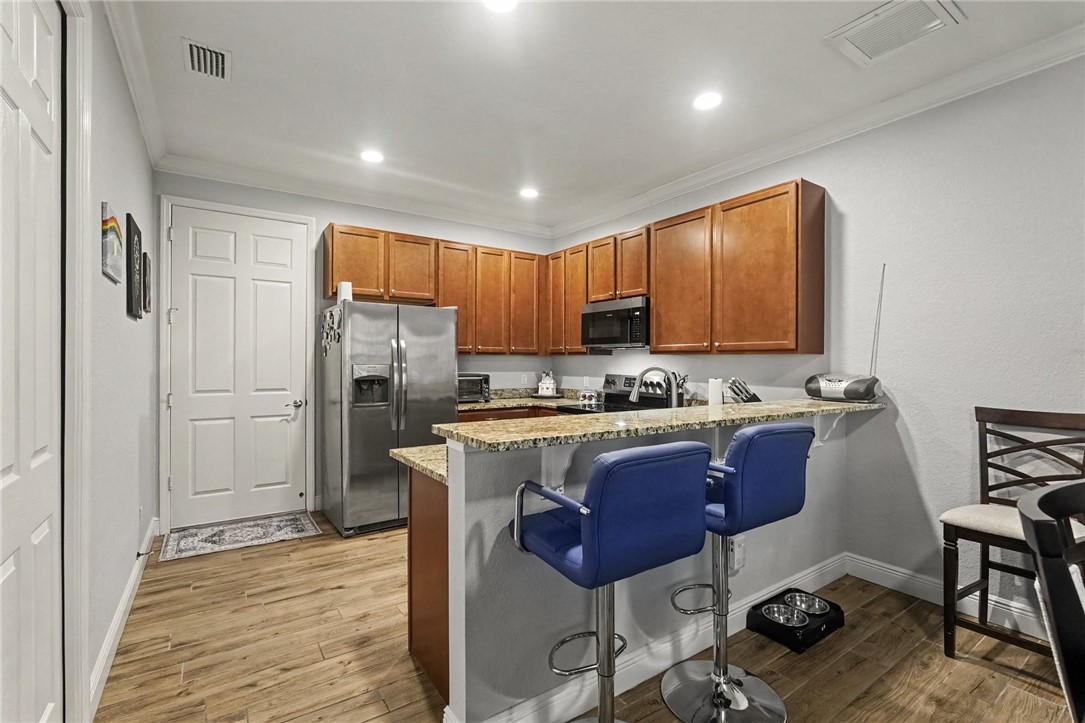 Kitchen featuring wood-finish flooring, recessed lighting, wood cabinetry, granite countertops, and stainless steel appliances