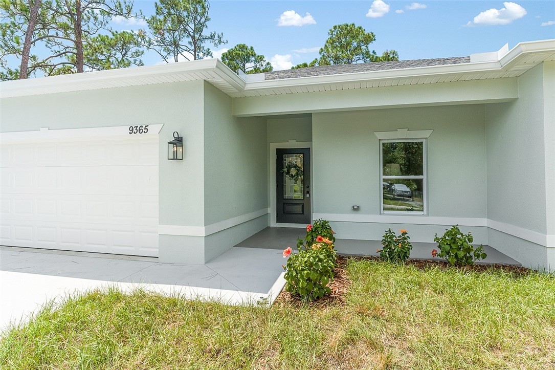 Smooth stucco exterior with an attached garage, covered entry, and decorative outdoor lighting