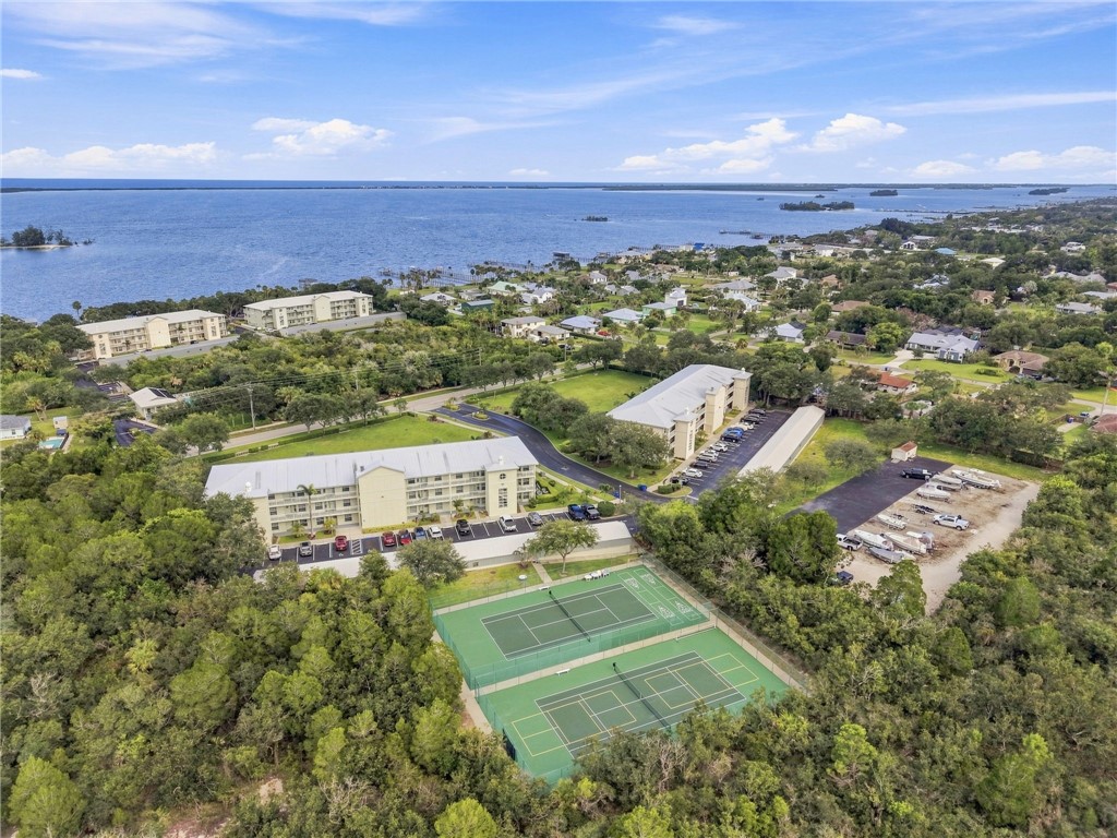 Expansive water body, multiple residential buildings, dual tennis courts, and a dedicated boat storage area