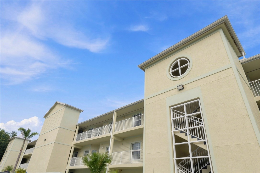 Multi-story building featuring stucco exterior, multiple private balconies with white railings, and an architectural round window accent