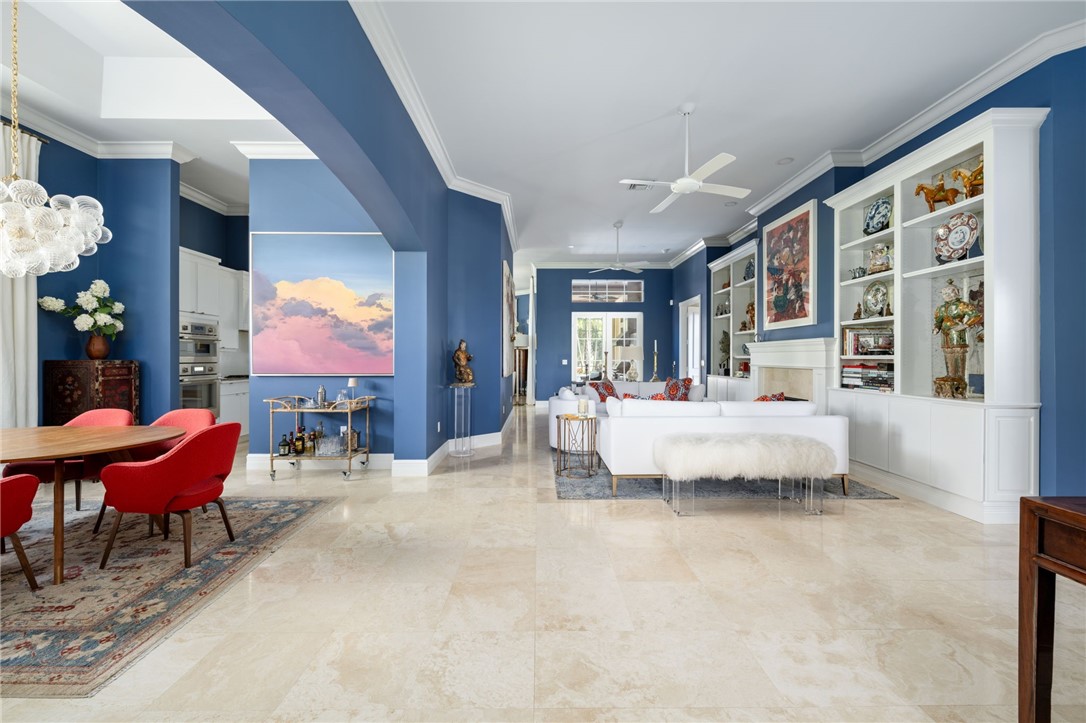 Spacious interior with light-toned tile flooring, extensive built-in shelving, crown molding, and a ceiling fan