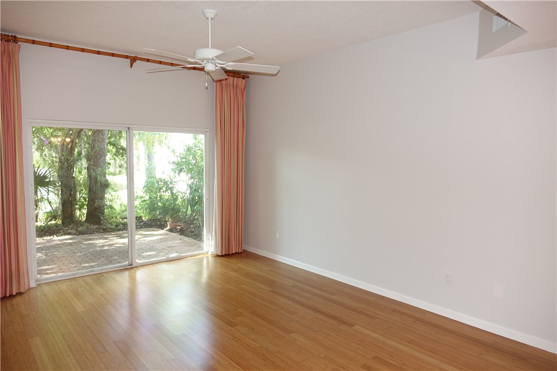 Hardwood flooring, sliding glass doors, white ceiling fan, vaulted ceiling, and exterior paver patio