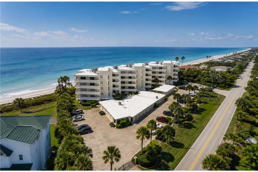 Multi-story condominium building featuring private balconies, direct beach frontage, and a dedicated parking area