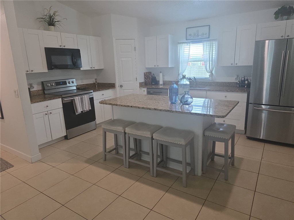 Bright kitchen featuring white cabinetry, granite countertops, and stainless steel appliances