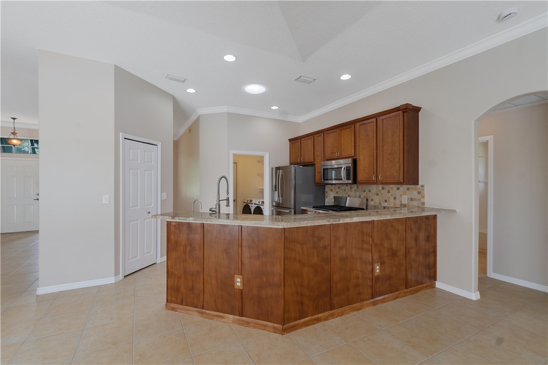 Spacious kitchen island featuring wood cabinetry, a granite-finish countertop, and a gooseneck faucet