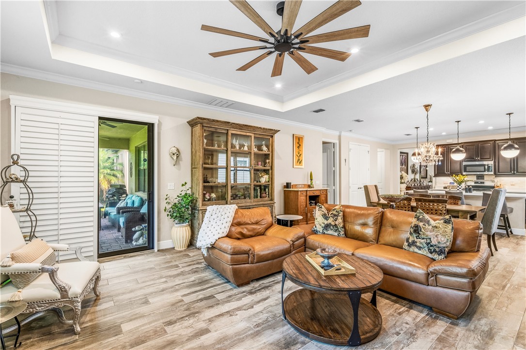 Spacious living area featuring coffered ceilings with recessed lighting, a multi-blade ceiling fan, and wood-finish flooring