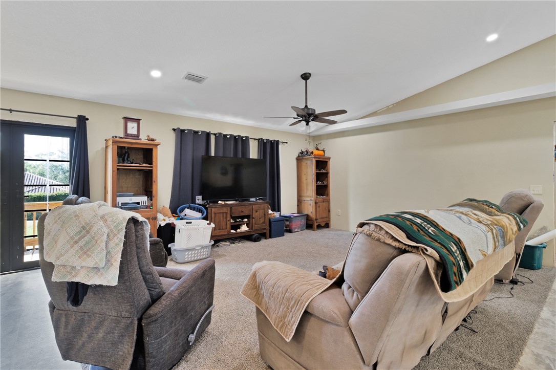 Carpeted living room with recessed lighting, lofted ceiling, french doors, and a ceiling fan
