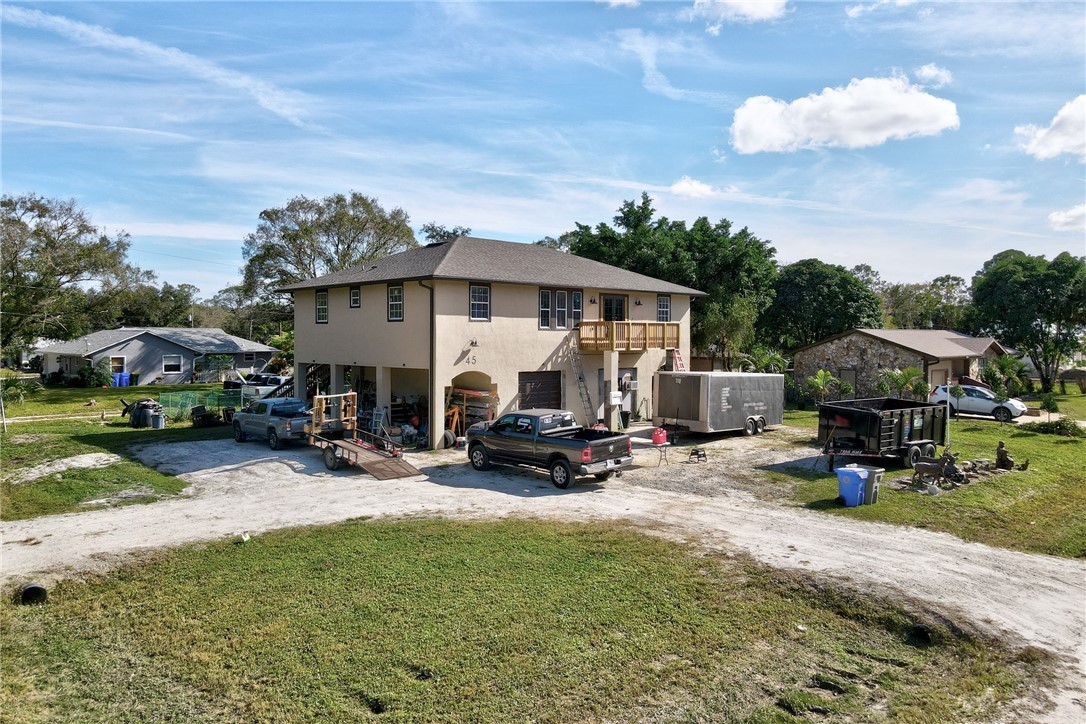 View of front facade with dirt driveway, a balcony, stucco siding, and a front lawn